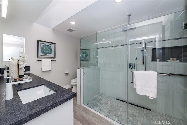 bathroom with a shower with door, vanity, wood-type flooring, and toilet