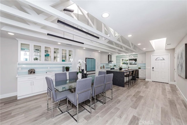 dining space with beam ceiling and light hardwood / wood-style flooring