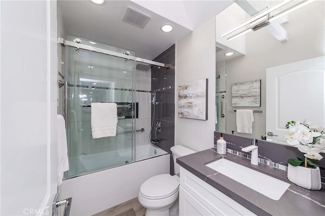 full bathroom featuring vanity, toilet, wood-type flooring, and enclosed tub / shower combo