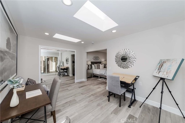 office space with a skylight and light hardwood / wood-style flooring