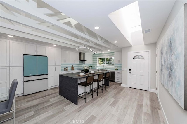 kitchen with a breakfast bar, white refrigerator, a center island, and white cabinetry