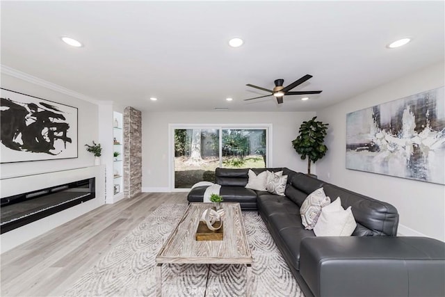 living room with ceiling fan, ornamental molding, and light hardwood / wood-style flooring