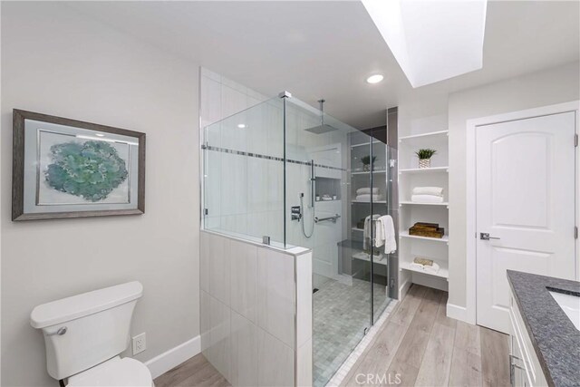 bathroom featuring wood-type flooring, vanity, toilet, and a shower with shower door