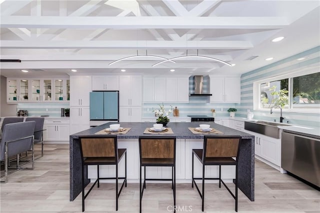 kitchen featuring appliances with stainless steel finishes, a center island, a kitchen breakfast bar, and wall chimney exhaust hood