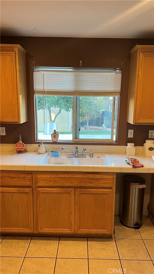 kitchen with tile counters, light tile patterned flooring, and sink