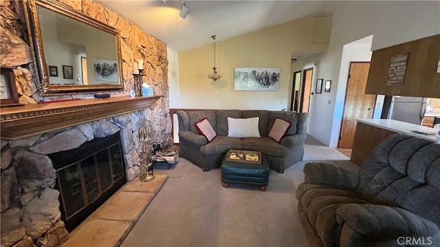 living room featuring a stone fireplace, light colored carpet, and vaulted ceiling