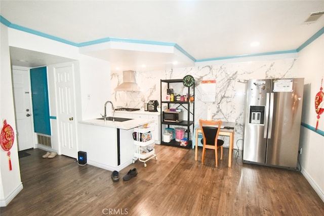 kitchen with appliances with stainless steel finishes, wall chimney exhaust hood, dark hardwood / wood-style floors, and sink