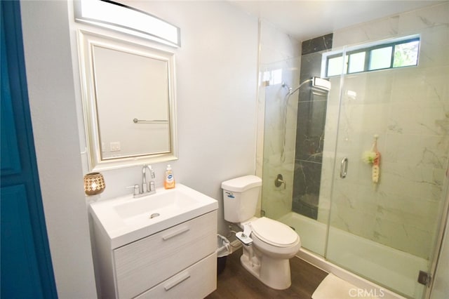 bathroom featuring vanity, a shower with shower door, hardwood / wood-style flooring, and toilet