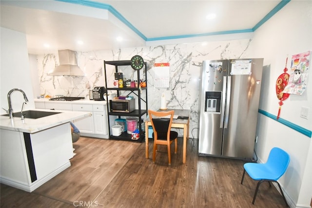 kitchen with wall chimney exhaust hood, dark wood-type flooring, stainless steel appliances, sink, and white cabinets