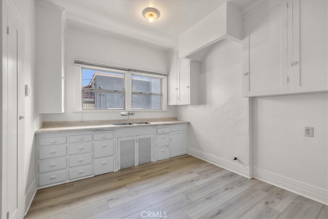 kitchen with sink, light hardwood / wood-style floors, and white cabinets