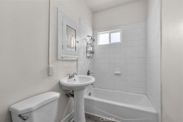 bathroom featuring tiled shower / bath combo and toilet