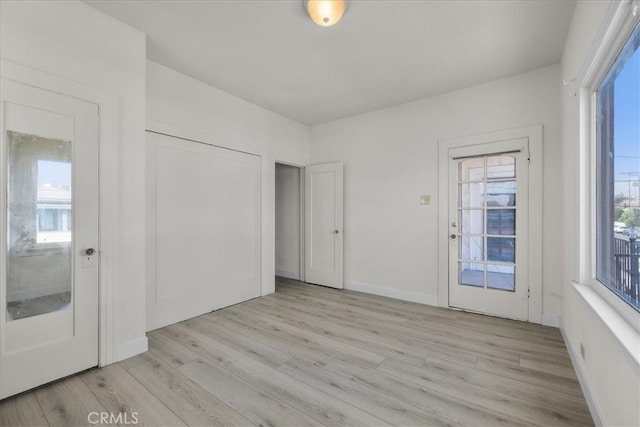 unfurnished bedroom with multiple windows, a closet, and light hardwood / wood-style floors