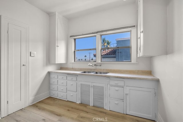 kitchen with sink, light wood-type flooring, and white cabinetry