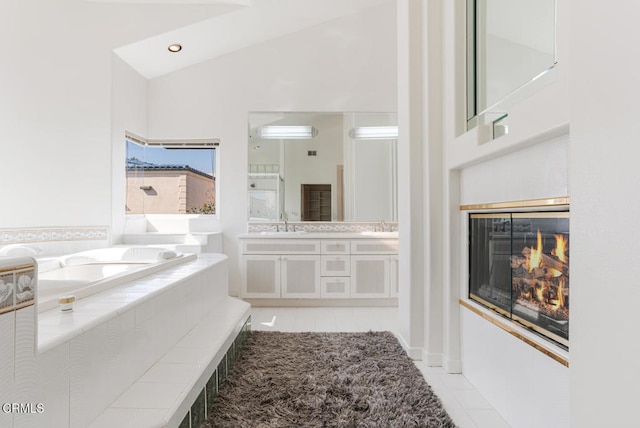 bathroom with tile patterned flooring, vanity, tiled tub, and vaulted ceiling