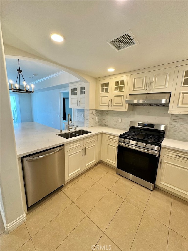 kitchen with sink, backsplash, white cabinets, appliances with stainless steel finishes, and light tile patterned floors