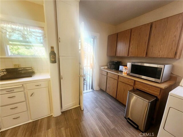 kitchen with dark wood-type flooring, washer / clothes dryer, and tasteful backsplash