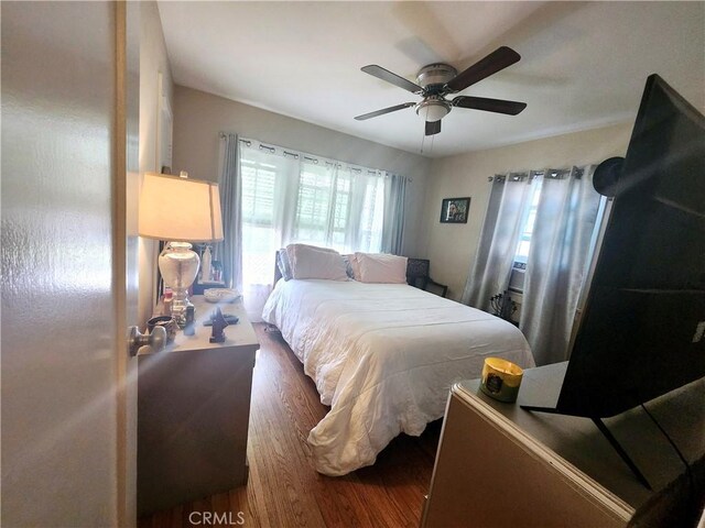 bedroom with dark hardwood / wood-style flooring and ceiling fan