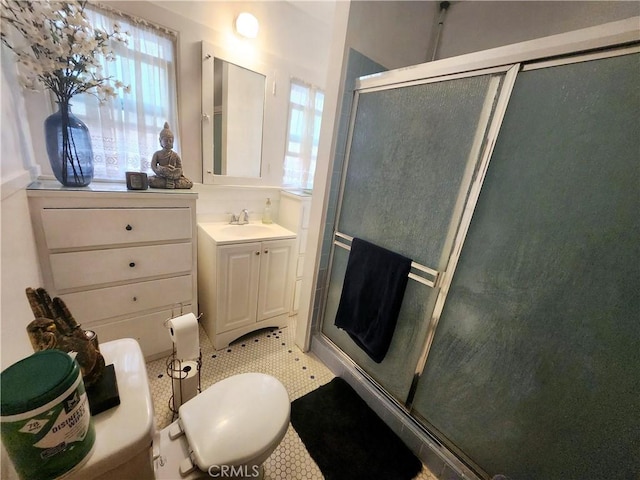 bathroom featuring tile patterned flooring, vanity, an enclosed shower, and toilet