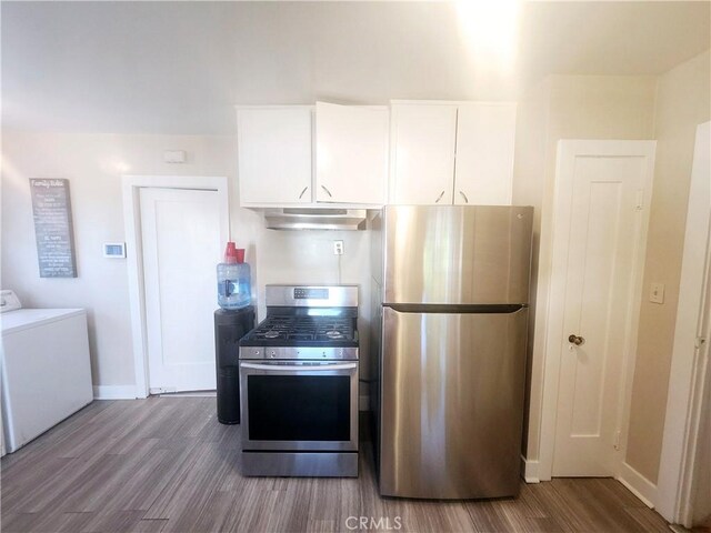 kitchen with ventilation hood, hardwood / wood-style flooring, separate washer and dryer, appliances with stainless steel finishes, and white cabinetry