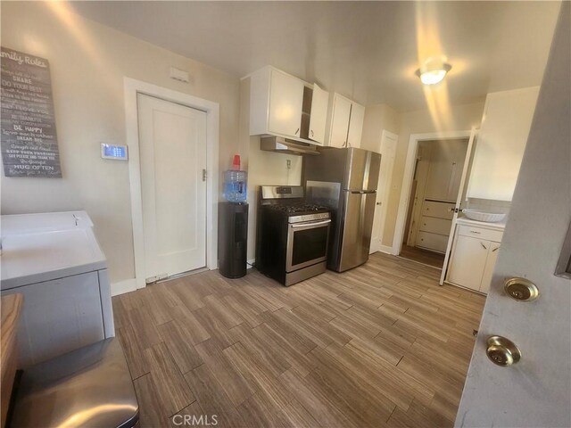 kitchen with stove, white cabinetry, stainless steel refrigerator, and light hardwood / wood-style flooring