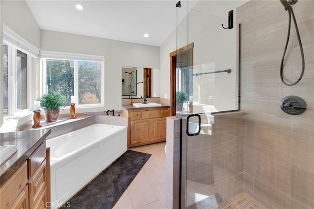 bathroom with shower with separate bathtub, vanity, and vaulted ceiling