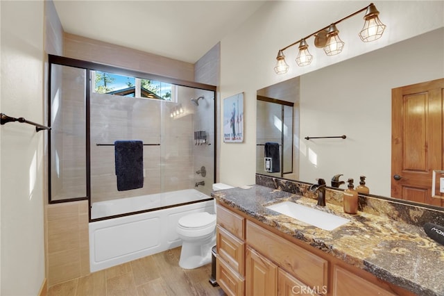 full bathroom with hardwood / wood-style floors, vanity, toilet, and bath / shower combo with glass door