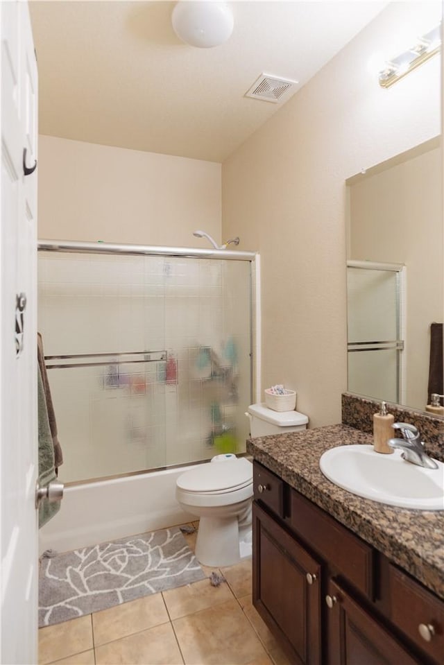 full bathroom featuring shower / bath combination with glass door, vanity, tile patterned flooring, and toilet