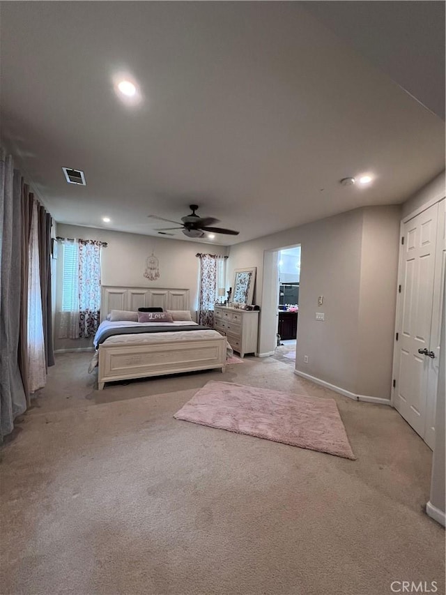 bedroom with multiple windows, ceiling fan, and light carpet