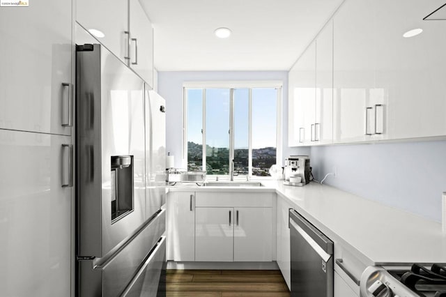 kitchen with white cabinets, stainless steel appliances, sink, and dark hardwood / wood-style flooring