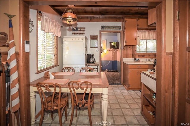 kitchen featuring beam ceiling, sink, stacked washer and clothes dryer, and wood ceiling