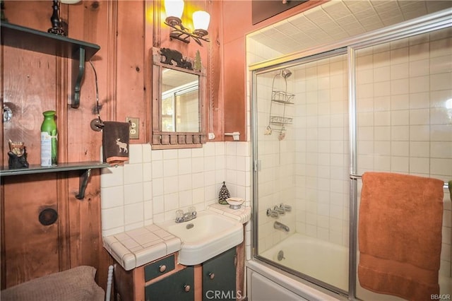 bathroom with vanity, backsplash, and bath / shower combo with glass door