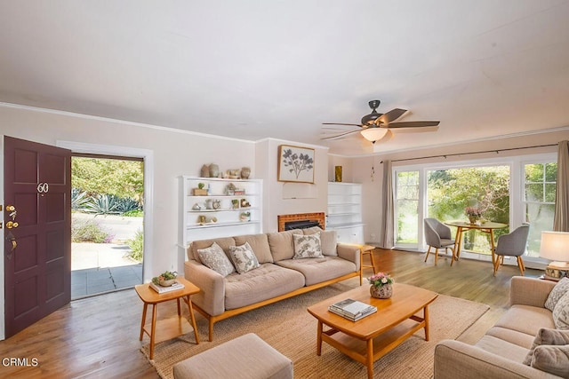 living room with crown molding, light hardwood / wood-style flooring, and ceiling fan