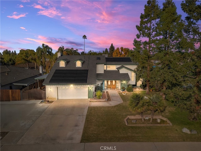 view of front of house with a lawn, a garage, and solar panels