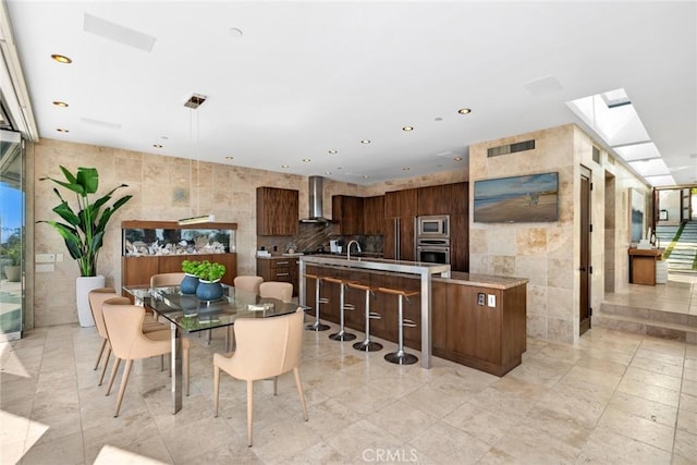 dining room with a skylight, sink, and tile walls