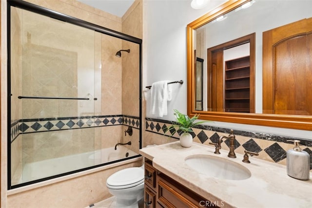 full bathroom featuring vanity, combined bath / shower with glass door, and toilet