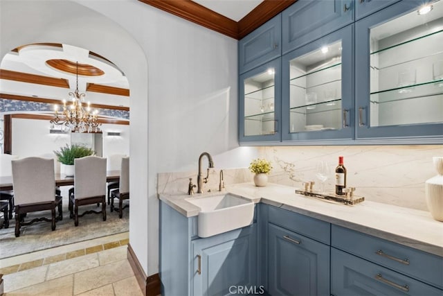 bar with blue cabinetry, tasteful backsplash, sink, and hanging light fixtures