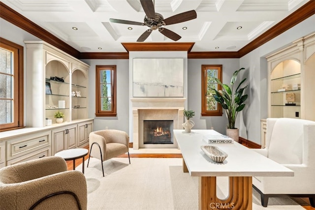 living area with ceiling fan, beamed ceiling, built in shelves, crown molding, and coffered ceiling