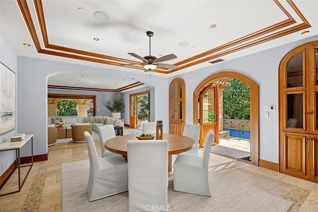 dining area with ceiling fan, a raised ceiling, and ornamental molding