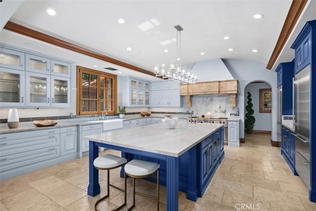 kitchen featuring a kitchen island, decorative backsplash, hanging light fixtures, blue cabinets, and light stone counters