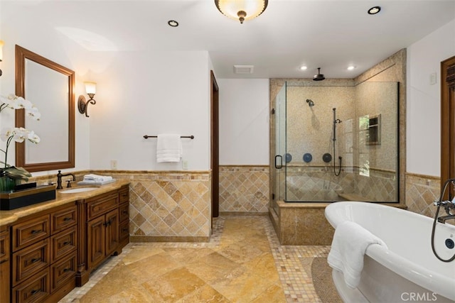 bathroom with tile walls, vanity, and separate shower and tub