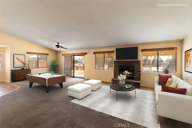 living room with vaulted ceiling, ceiling fan, a brick fireplace, and carpet flooring