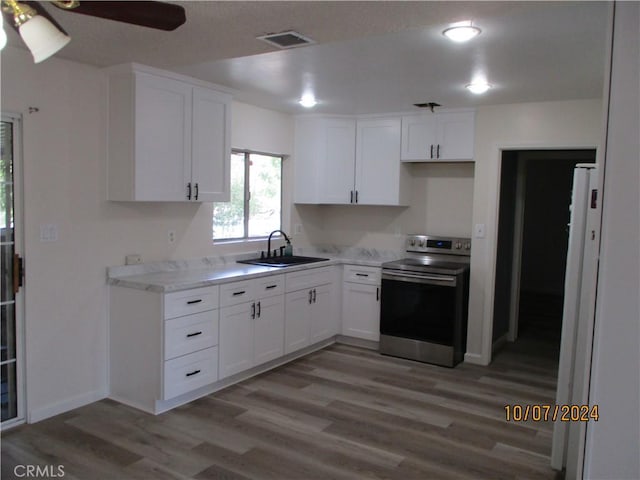 kitchen with white cabinetry, sink, ceiling fan, stainless steel range with electric stovetop, and hardwood / wood-style flooring