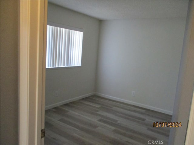 spare room featuring a textured ceiling and dark wood-type flooring