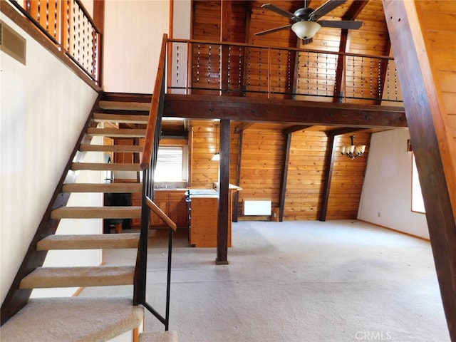 stairway featuring carpet floors, wood walls, and ceiling fan