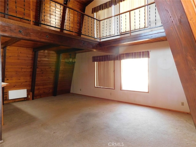 unfurnished living room with a high ceiling, beamed ceiling, and carpet floors