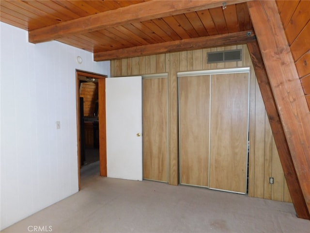 unfurnished bedroom featuring wooden ceiling, beamed ceiling, light colored carpet, and wooden walls