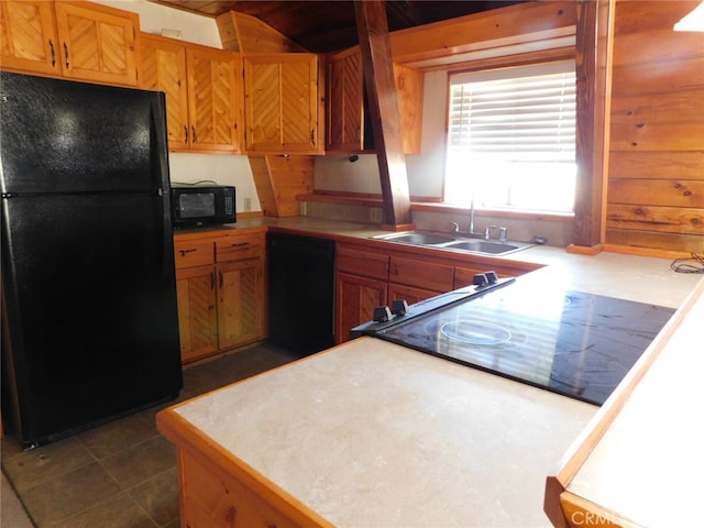 kitchen featuring wood walls, sink, dark tile patterned floors, and black appliances