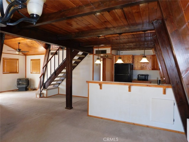 kitchen featuring wood ceiling, black fridge, pendant lighting, a breakfast bar area, and light colored carpet