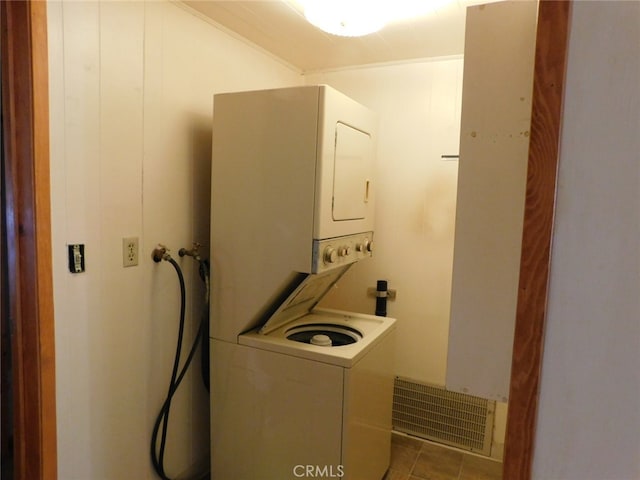 laundry room featuring stacked washer and dryer and light tile patterned flooring