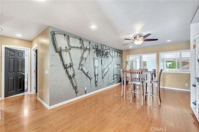 unfurnished dining area with ceiling fan and light wood-type flooring